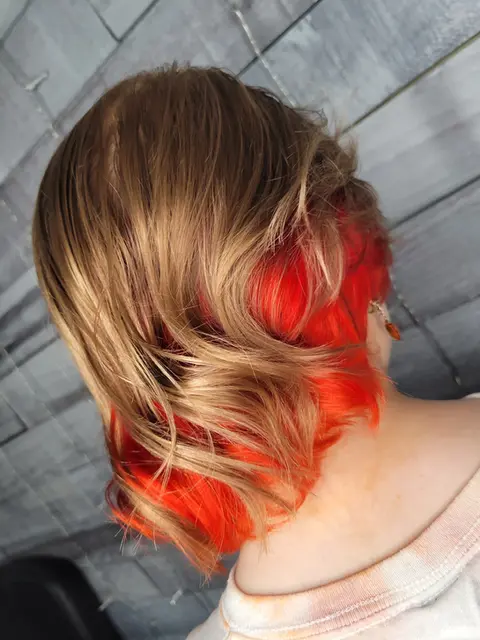 Back view of peek-a-boo red highlights on natural brown hair.