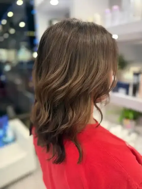 Side view of brunette hair with soft waves and subtle dimension.