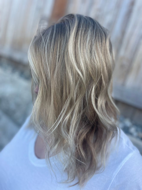 Blonde balayage hair with loose waves and subtle dimension.