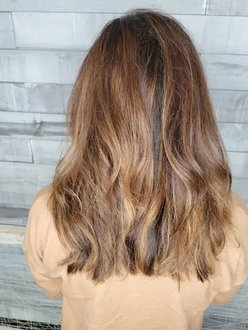 Back and side views of long, layered hair with a natural balayage blending dark roots into caramel ends.