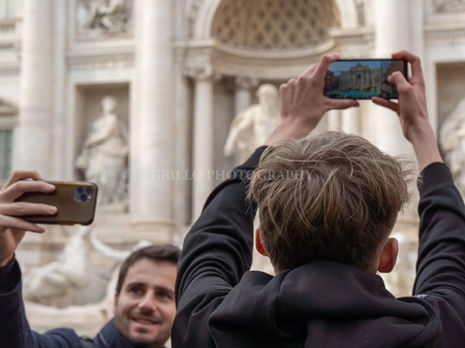 Two men take photographs of the Trevi Fountain with their phones in Rome, on February 12, 2025.