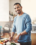 A happy, healthy man chopping vegetables in his kitchen and smiling