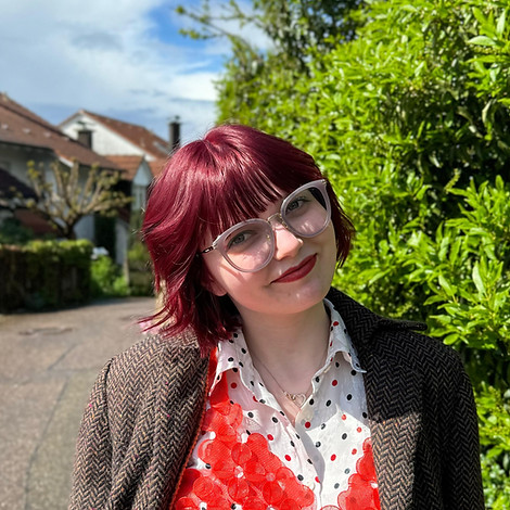 Girl with purple/red hair standing in the sunshine on a road