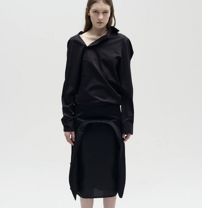 A black deconstructed dress shirt featuring an asymmetrical button closure and tailored fit, created from a second-hand garment. This circular design showcases high-end remake expertise, developed and produced in-house by XV Production in Sweden to promote sustainable fashion. A showcase of high-end sustainable fashion and remake expertise, designed and produced in Sweden. This garment highlights circular craftsmanship, utilizing upcycled materials and ethical manufacturing processes. Expertly realized through in-house design development, remake techniques, and local production at XV Production, Borås – driving the transition towards a circular textile industry.