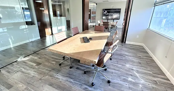 West Conference Room at West Valley Coworking in Glendale, AZ with a large meeting table, TV, whiteboard and comfortable seat