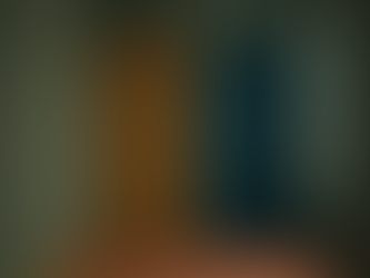 A hallway with mustard yellow and teal doors side by side on green walls, set on a brown carpet, creating a moody atmosphere.