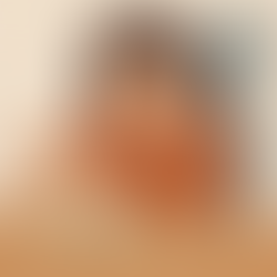 A person in an orange shirt appears pensive while arranging sticky notes on a wooden table. The setting has a simple, muted background.