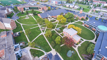 Education campus with academic buildings, walkways, open grounds, and surrounding roads