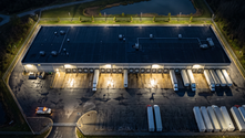 Aerial view of a fenced industrial warehouse with loading docks, parked trailers and a retention pond at night Excerpt: A breach at a hazardous materials warehouse isn't only a th