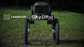 Four-wheeled robot on grassy field with LandskyAI SkyBlog logo text overlaid, dark forest background.
