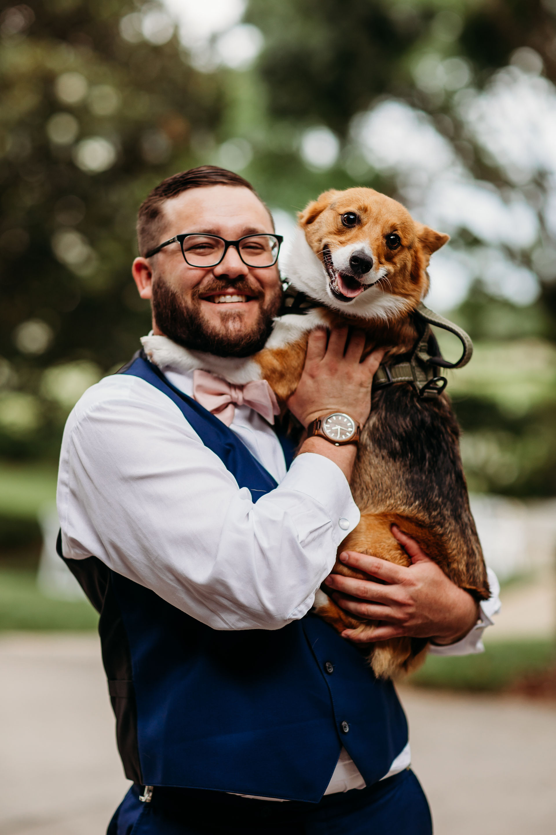 Groom taking a photo with his corgi on wedding day