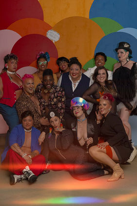 Group of diverse people posing in front of a colorful background.