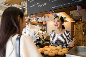 Smiling woman working at bakery and displaying fresh scones.