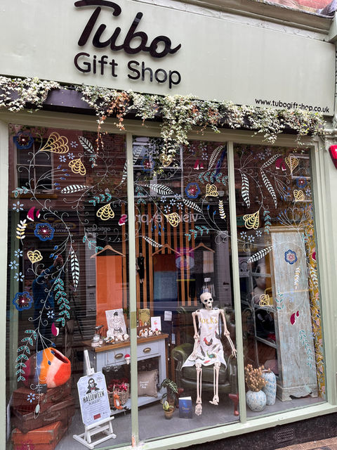 Organic shapes of flowers, leaves and petals painted in a soft drape over three panes glass window of shop frontage in Derby city centre.