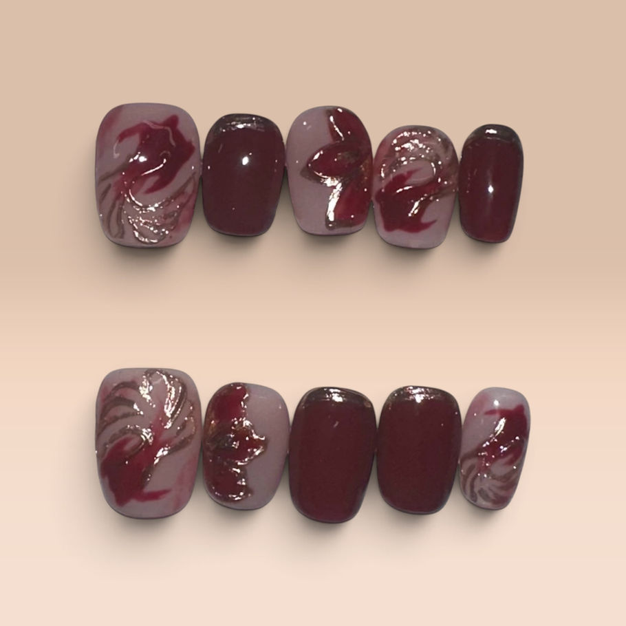 Crimson Koi press-on nails featuring deep crimson and blush pink tones with metallic gold koi-inspired accents and delicate gold detailing.