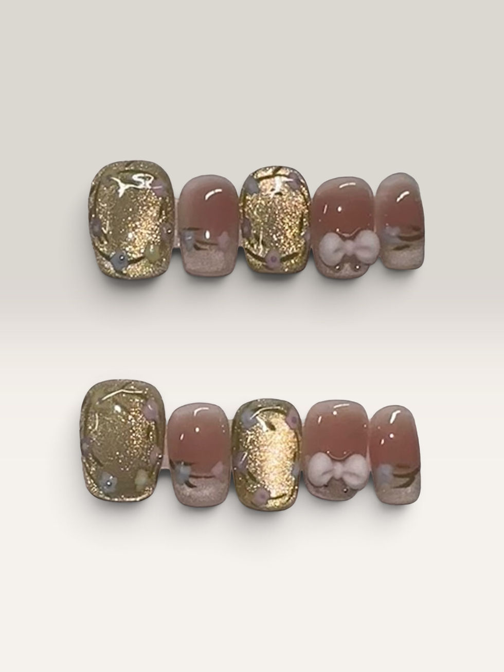 Gilded Blush press-on nails by M Press Beauty featuring soft blush pink, shimmering gold accents, delicate floral details, and 3D bow embellishments.