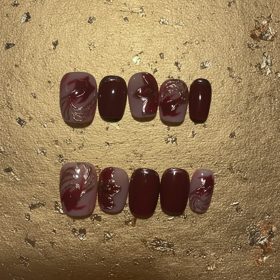 Crimson Koi press-on nails featuring deep crimson and blush pink tones with metallic gold koi-inspired accents and delicate gold detailing.