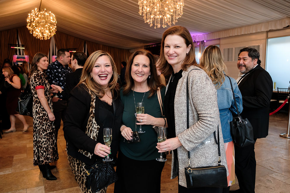 Group of women laughing together while holding champagne at a party