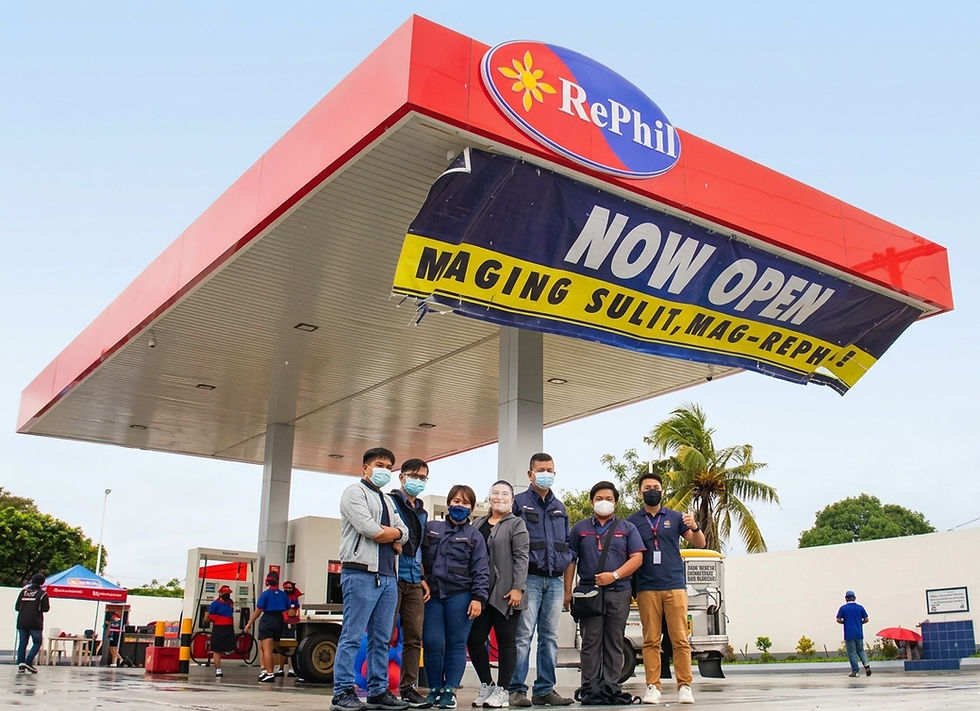 Grand opening of a RePhil gas station with the team proudly posing under a large "Now Open" banner, marking the start of service with smiles and enthusiasm.