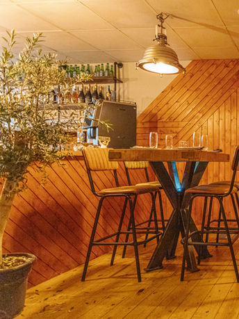 Wooden bar with stools, lights and decor inside Cinnamon And Olives restaurant.