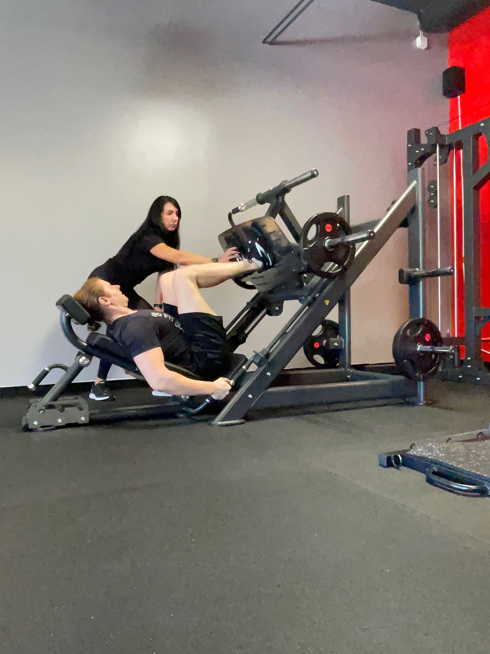Personal trainer Deidre helping client with leg press at SoFit Huntington Beach