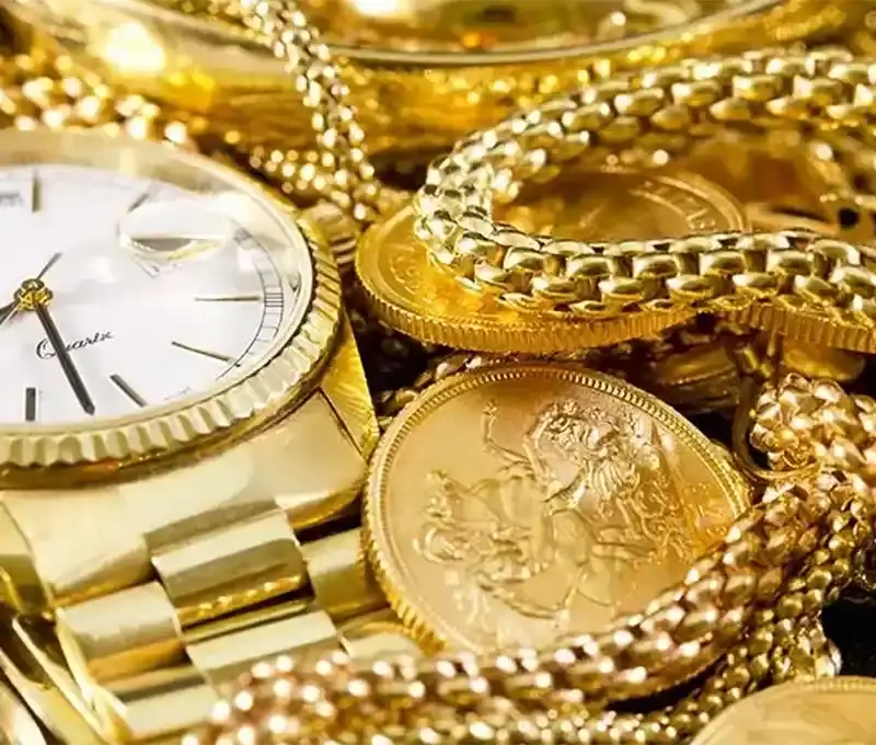 An example of types of gold we would purchase.
Gold watch and chain among gold coins with detailed engravings.