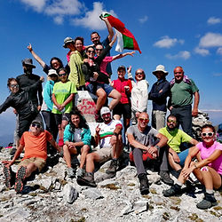 Усмихната група на Summits Trek празнува изкачен връх с българското знаме по маршрута Е4.