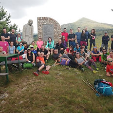 Групата на Summits Trek почива край паметник в планината по маршрута Е4 Витоша–Славянка.