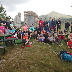 Групата на Summits Trek почива край паметник в планината по маршрута Е4 Витоша–Славянка.