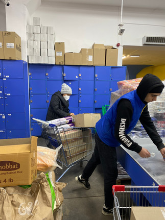 Two people working on checking out the boxes and putting them in a cart. 