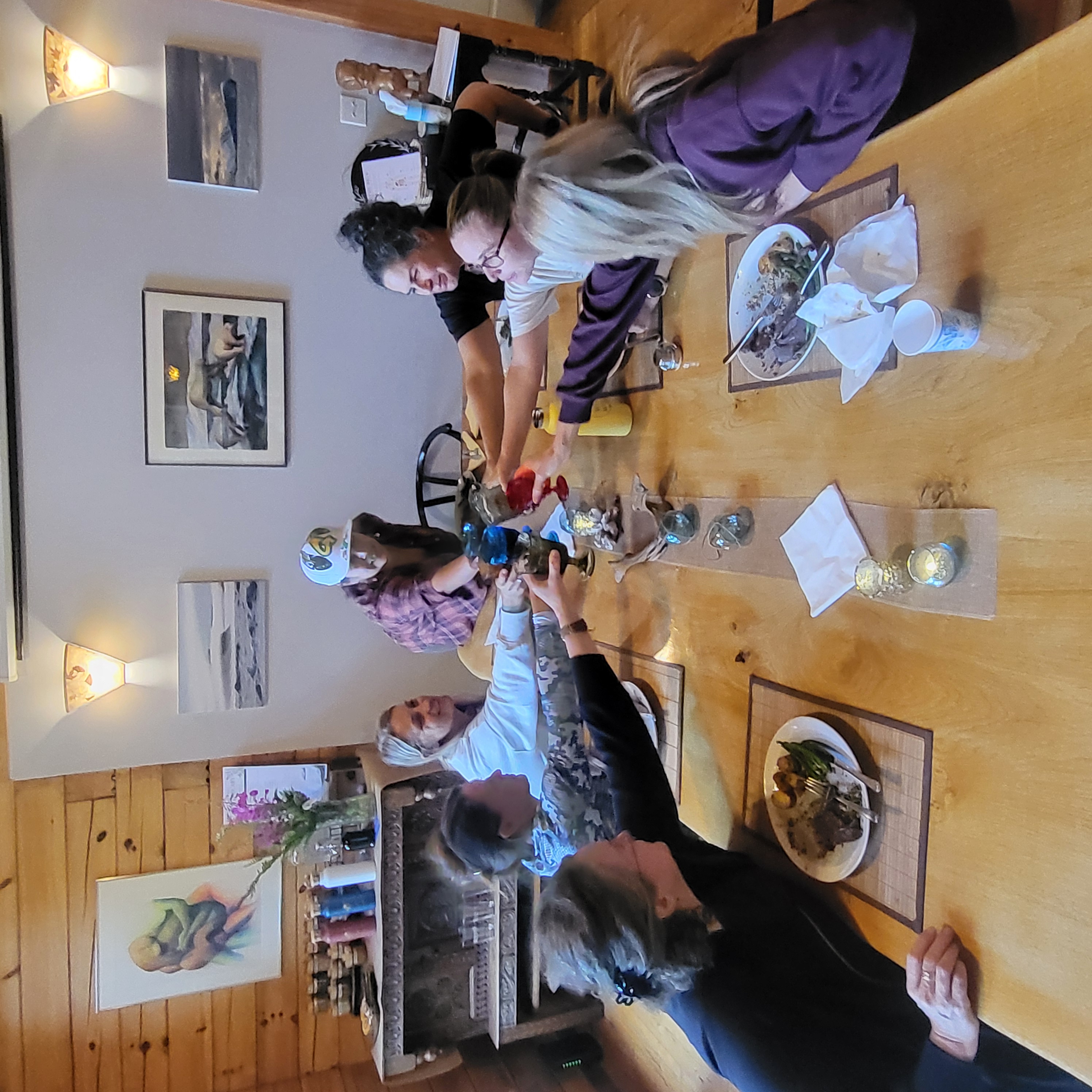 Women raising their glasses in a toast around a long shared dinner table