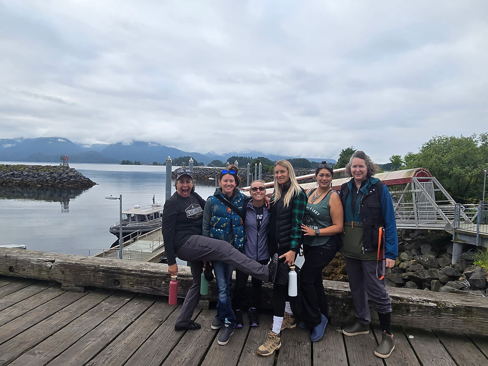 Group of women posing on a dock with the water and mountains of Sitka behind them