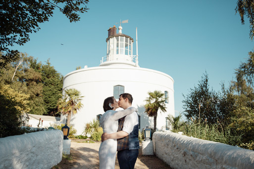 Bride and groom sharing their first kiss in front of The Usk Lighthouse, South Wales.