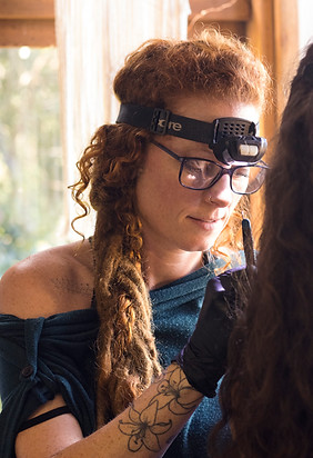 portrait of Lucy Brown tattoo artist with red hair wearing glassess