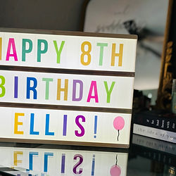 Light up sign that says "Happy 8th Birthday Ellis" in multi color letters
