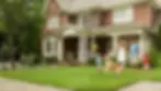 Family of four with golden retriever playing in front yard of brick home.webp