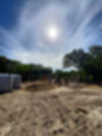Construction site in Belize, with labourers mixing concrete for a foundation. Materials and water cisterns are seen on site