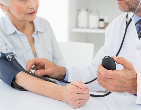 Doctor taking blood pressure of older patient