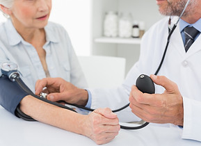 Doctor taking blood pressure of older pa