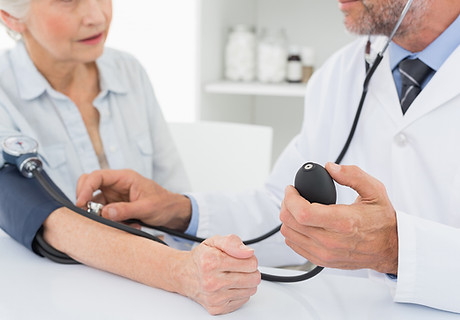 Doctor taking blood pressure of older pa