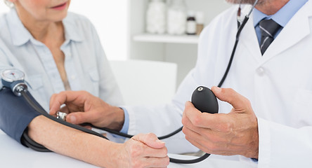 Doctor taking blood pressure of older pa