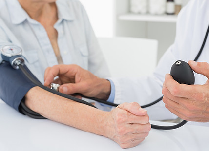 Doctor taking blood pressure of older patient