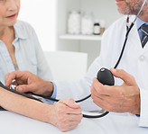 Doctor taking blood pressure of older pa