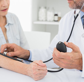 Doctor taking blood pressure of older patient