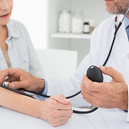 Doctor taking blood pressure of older patient