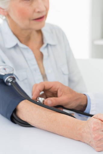 Doctor taking blood pressure of older pa
