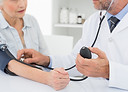 Doctor taking blood pressure of older pa