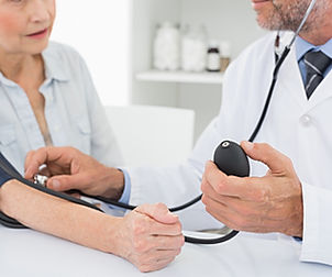 Doctor taking blood pressure of older patient