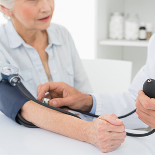 Doctor taking blood pressure of older pa