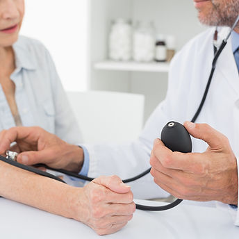 Doctor taking blood pressure of older patient